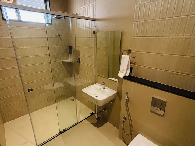 Bathroom with a glass shower cubicle and beige textured tiles