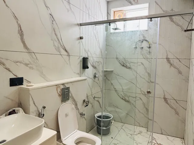 Suite bathroom in white marble-look tile with glass shower and basin cabinet