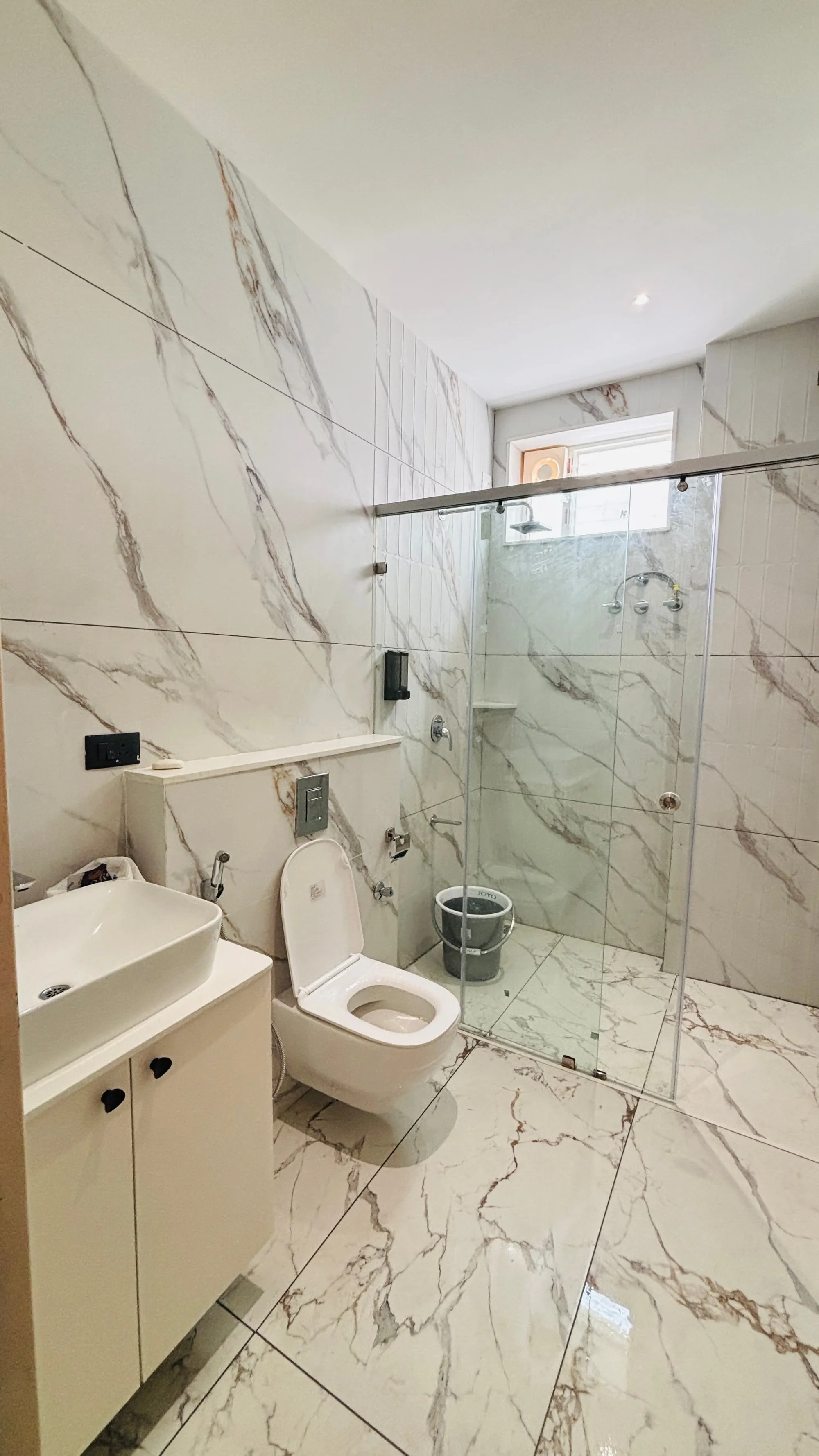 Superior King bathroom at Aakarsh Inn in white marble-look tile, with a glass shower and a basin cabinet