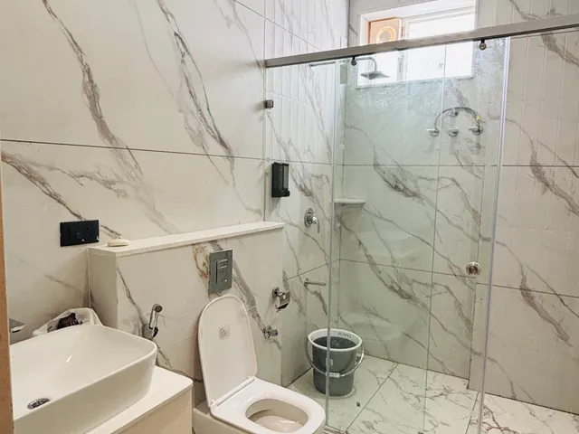 Bathroom in white marble-look tile with a glass shower and basin cabinet