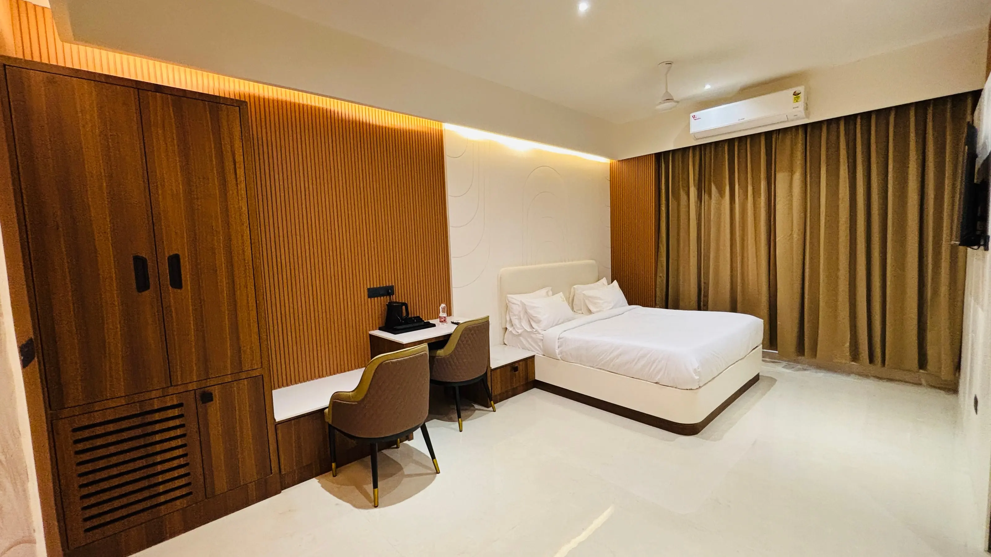 Suite Room at Aakarsh Inn with a king bed, walnut wardrobe wall and mustard curtains
