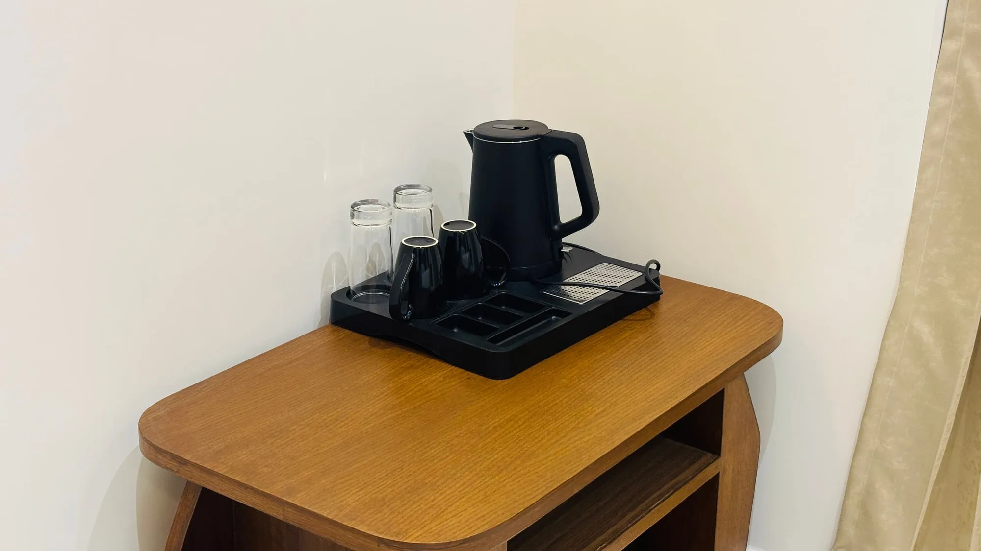 Electric kettle, cups and bottled water set out on a tray in a guest room