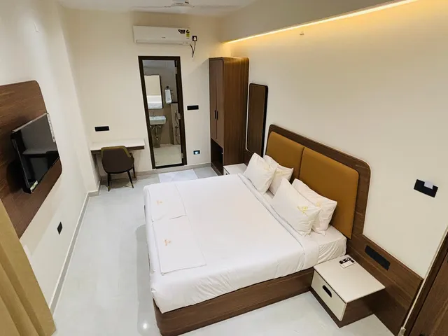 King bed with white linen and a padded headboard, seen from the entrance
