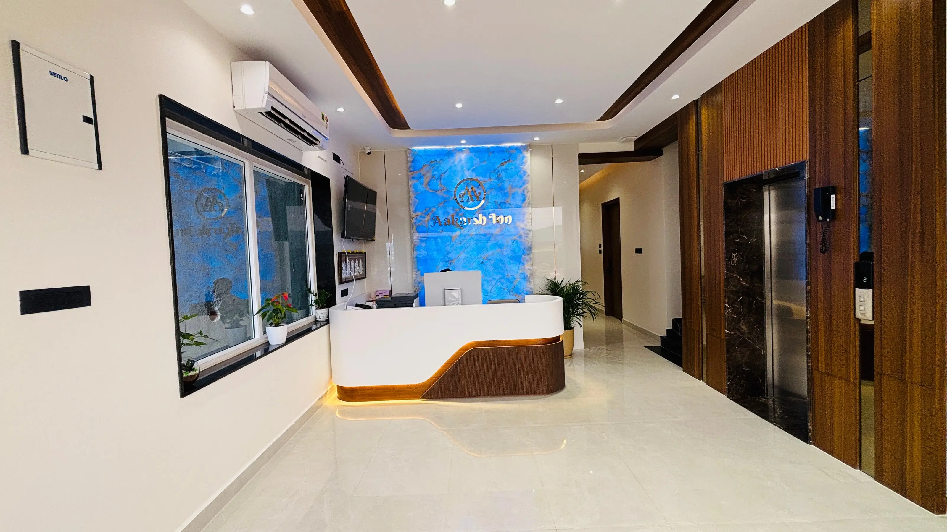 The reception desk at Aakarsh Inn, with the hotel nameplate lit on the wall behind it