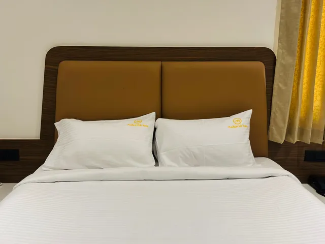 Queen bed with a tan upholstered headboard and white bedding